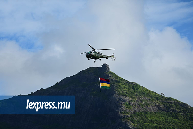 ■ Le drapeau national porté par un hélicoptère avec en toile de fond la chaîne de montagnes de Moka..jpeg
